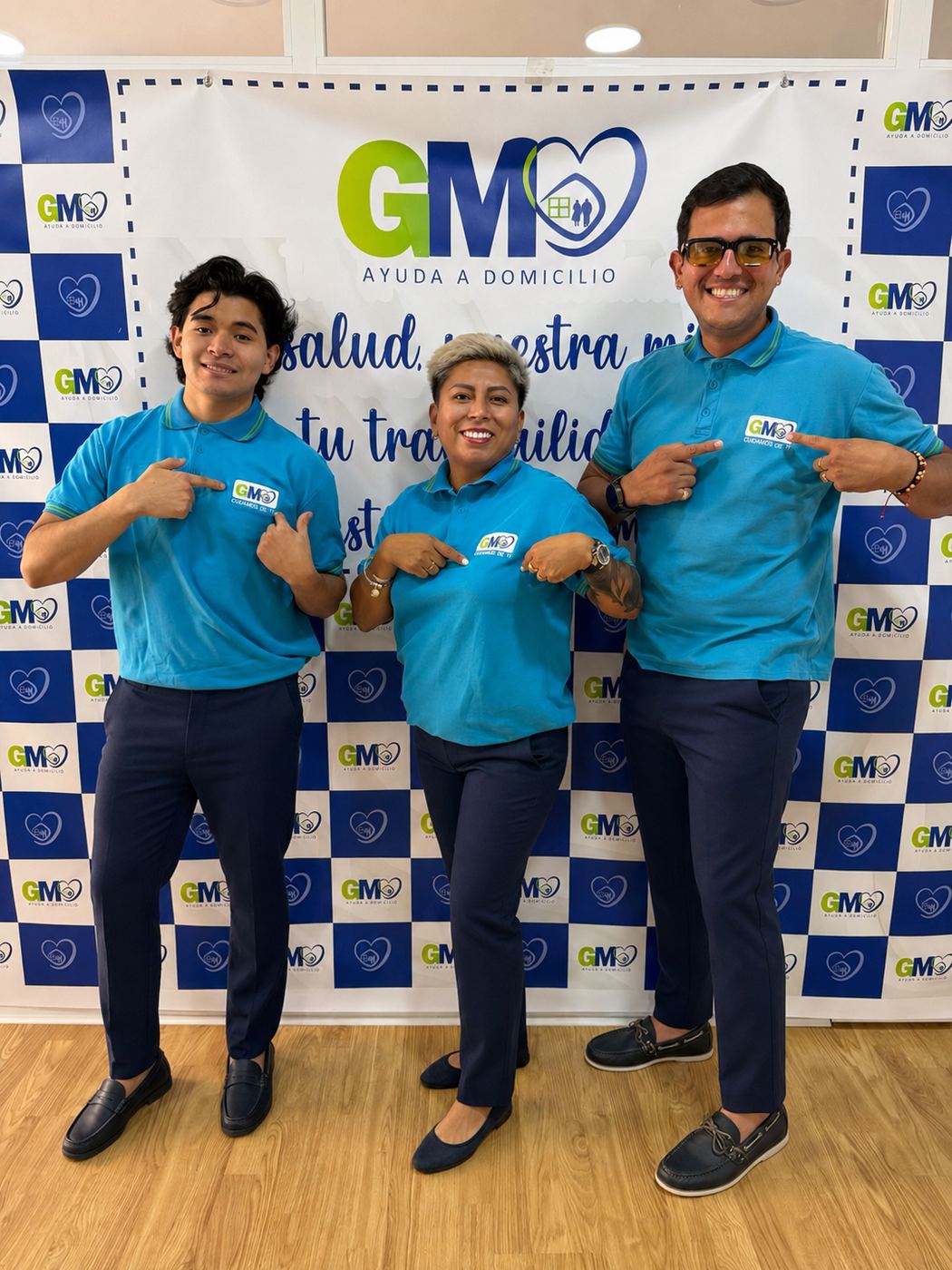 Equipo de GM Ayuda a Domicilio señalando su logo, transmitiendo orgullo de pertenencia